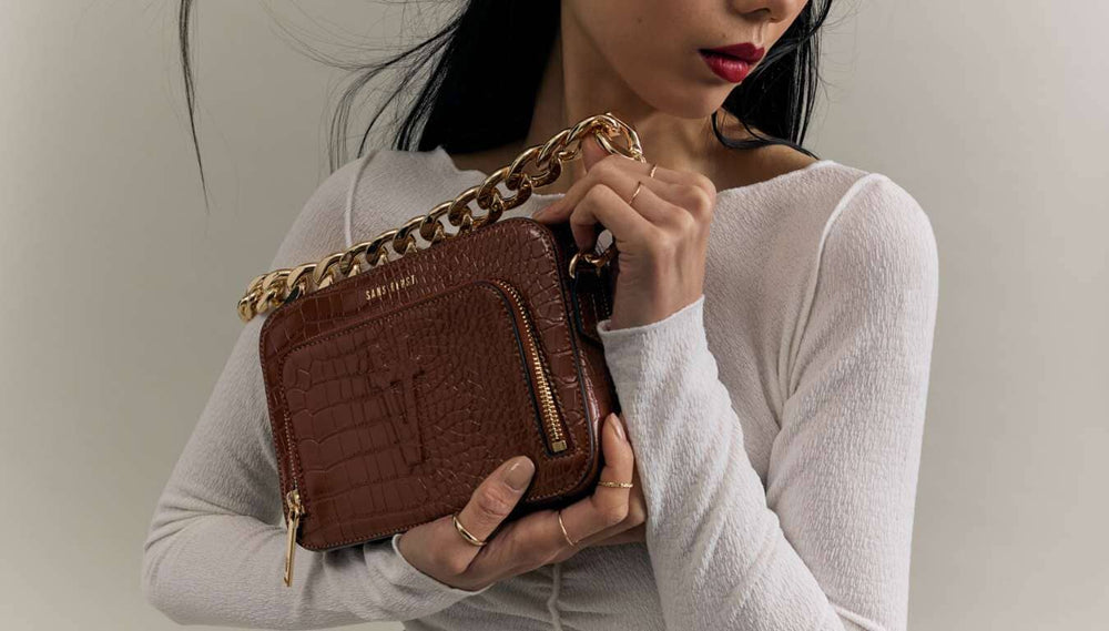 Yixin carries the Sojourn vegan leather handbag in Mahogany brown, styled with the Elemental Chain Strap in Gold