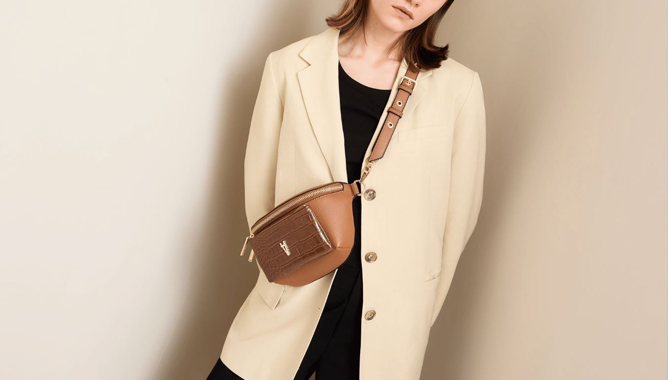 Cropped image of Tari wearing a pale neutral blazer, grey tank + the Bright Spark Crossbody bag in Cinnamon