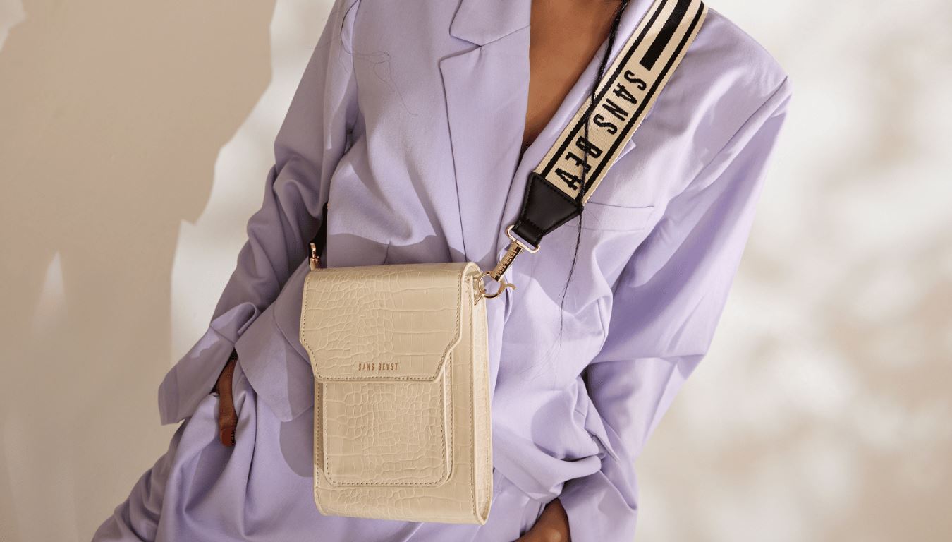 April wears a pale Lavender suit with the Bandolier in Pale Vanilla and Corridor Strap in Licorice Gold